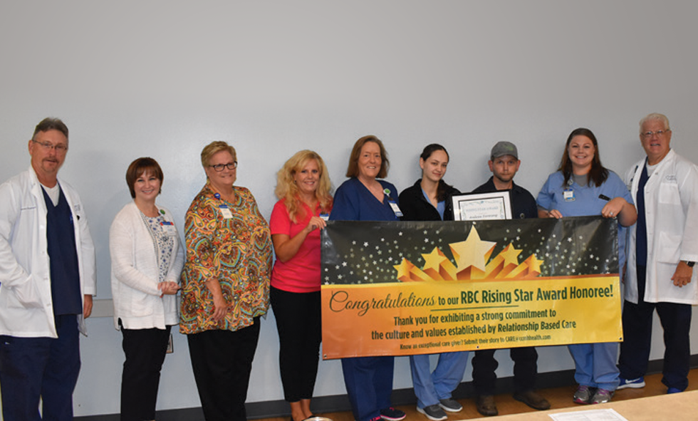CCMH Faculty holding Rising Star Award banner with Andrew Fanning