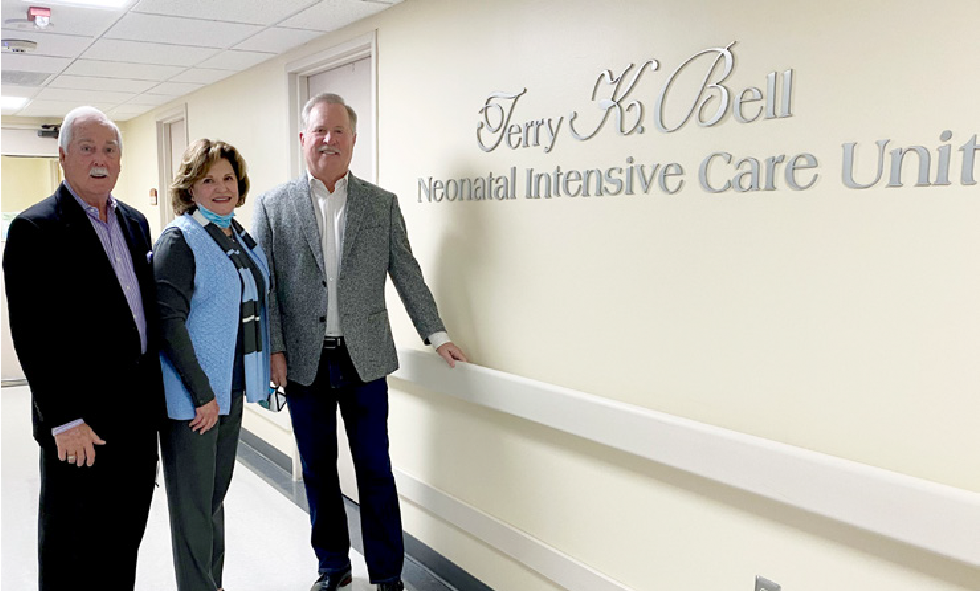 Mike Mayhall, Janice Bell, and Richard Allen standing next to new Terry K. Bell Neonatal Intensive Care Unit wall