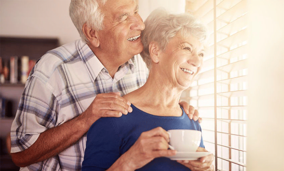 Older man and woman looking out window and smiling