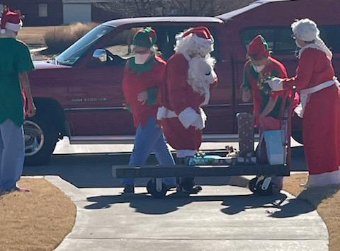 MTNRC employees dressed as Santa, Mrs. Claus, and Christmas elves arranging presents on a sleigh