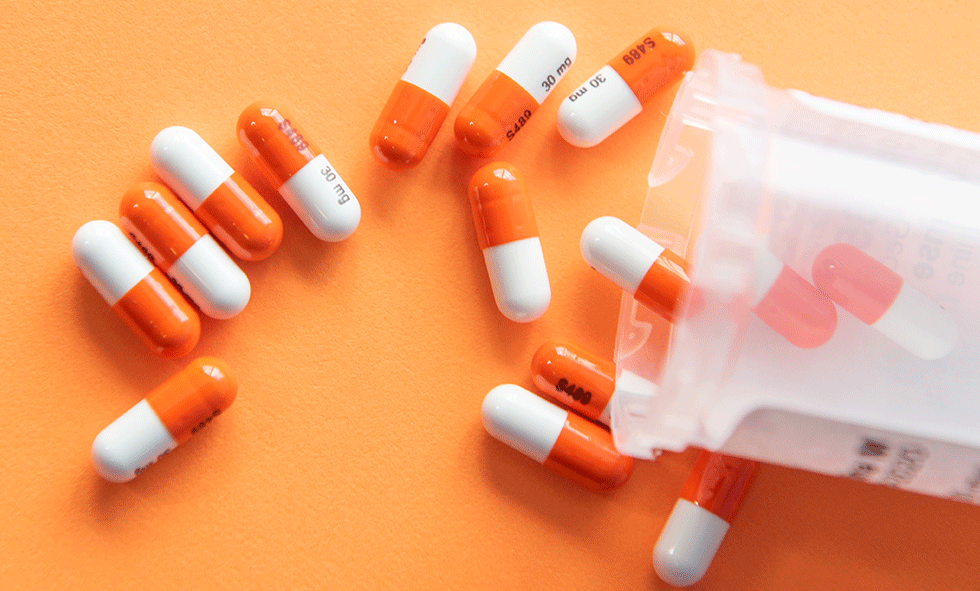 Orange background with white & orange pills across - prevent drug overdose