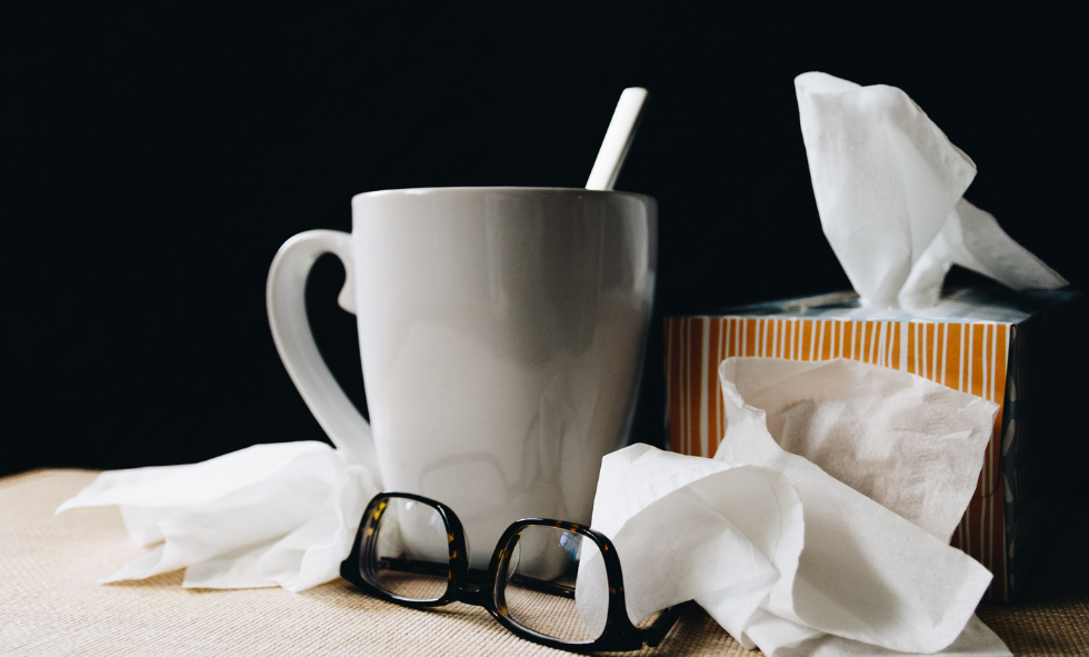 Tissues with mug and glasses sitting on a desk - cold treatment