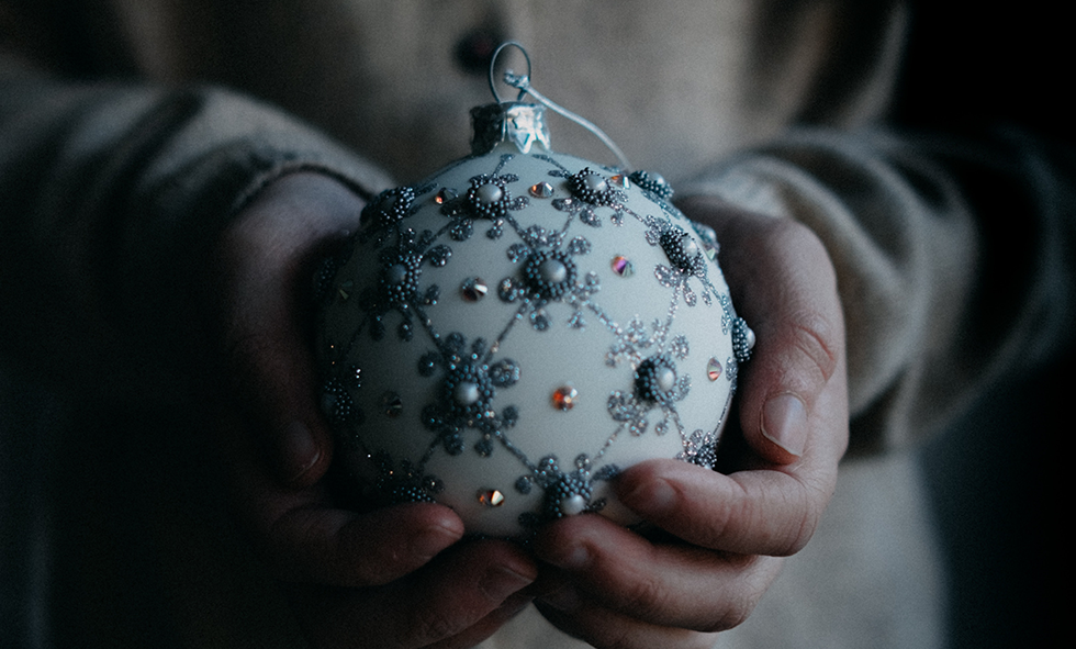 Woman in dark holding Christmas ornament in hands