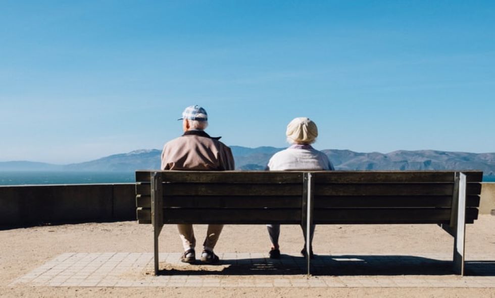 two older people sitting outside on a bench looking out at a mountain - Alzheimer's awareness