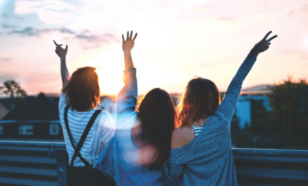 three women celebrating womens health taking a group picture outside with their backs facing the camera