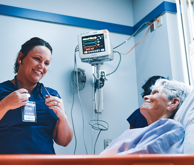 Nurse smiling and talking with elderly patient in hospital room Nurse smiling and talking with elderly patient in hospital room